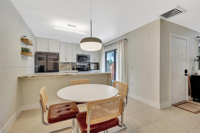 dining area featuring light tile patterned flooring, visible vents, and baseboards