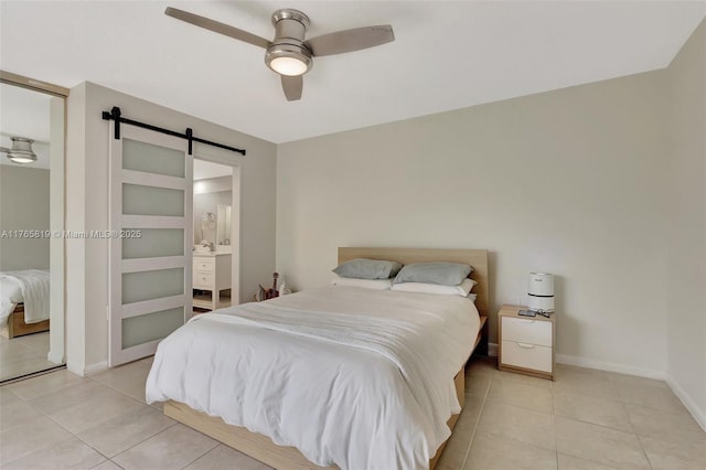 bedroom featuring connected bathroom, a barn door, light tile patterned floors, ceiling fan, and baseboards