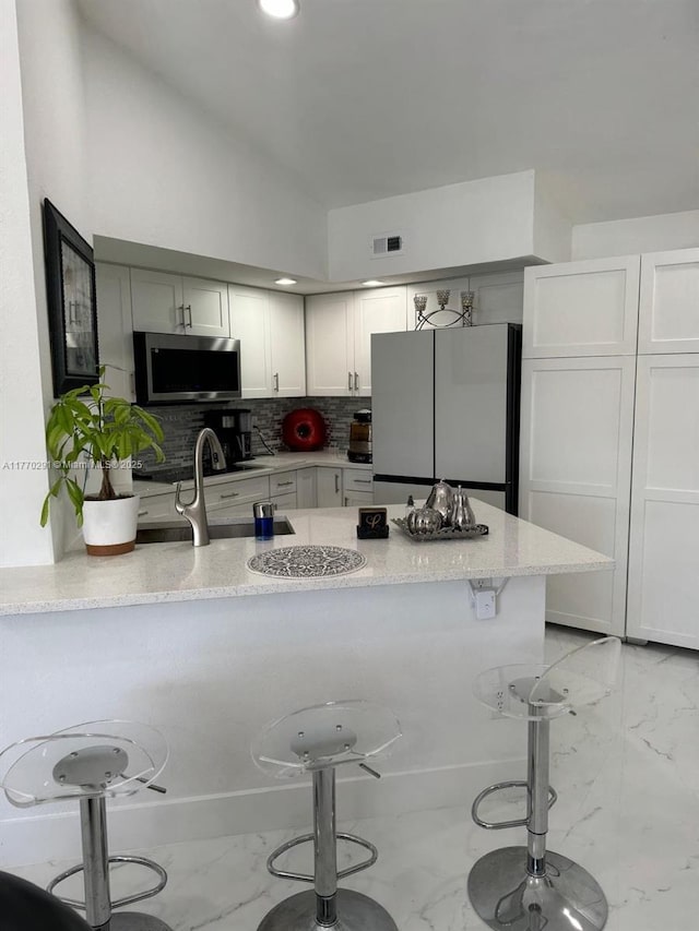12650 Vista Isles Dr Unit 923, Sunrise, FL 33325 - kitchen featuring a breakfast bar area, stainless steel microwave, light stone counters, and freestanding refrigerator