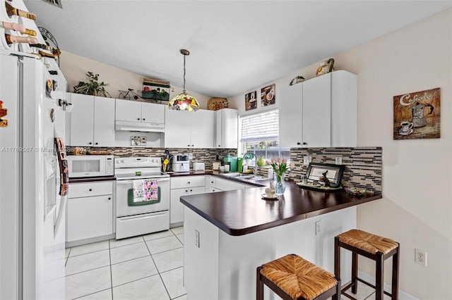 14930 SW 178th Ter, Miami, FL 33187 - kitchen with a peninsula, white appliances, dark countertops, a sink, and light tile patterned floors