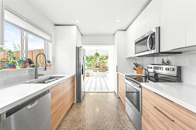 kitchen featuring light speckled floor, stainless steel appliances, decorative backsplash, a sink, and modern cabinets