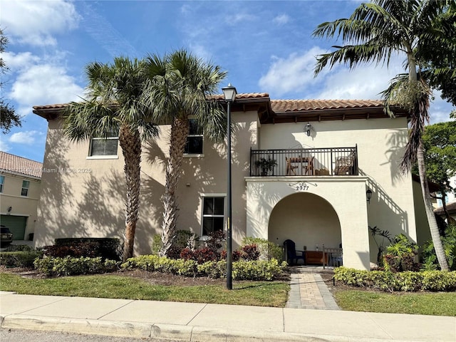 view of front of property with a balcony, a tile roof, and stucco siding