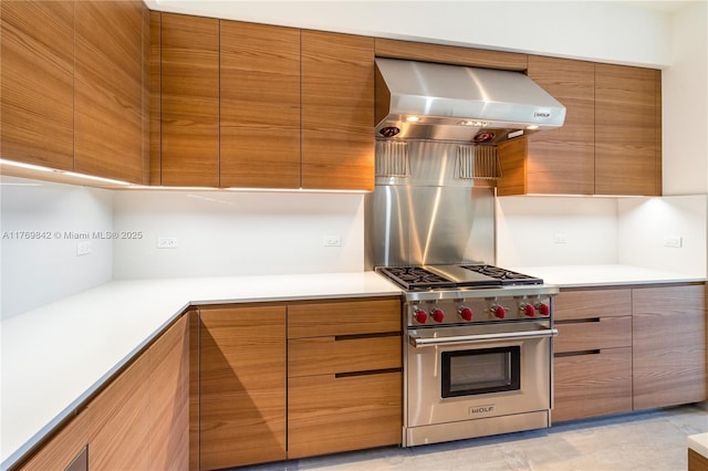kitchen featuring light countertops, modern cabinets, designer stove, wall chimney range hood, and brown cabinetry