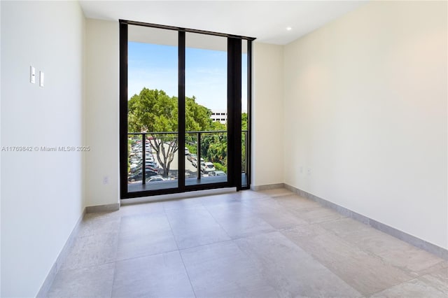 unfurnished room with a wall of windows, a wealth of natural light, and baseboards