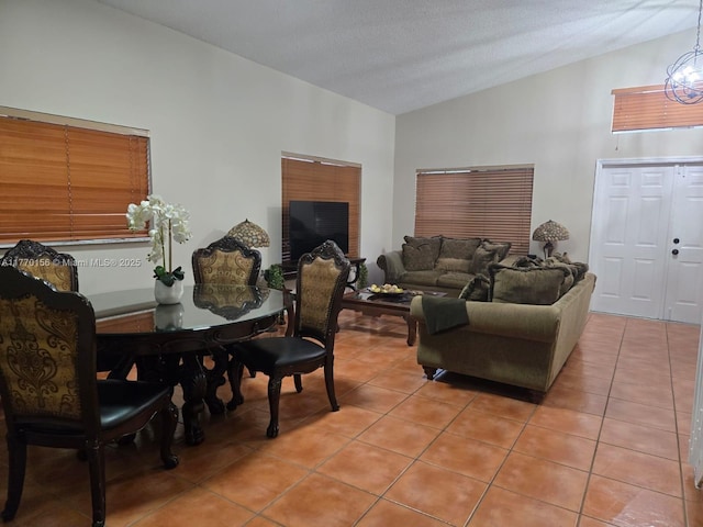 dining area with a textured ceiling, vaulted ceiling, and light tile patterned floors