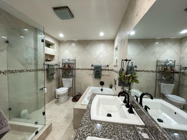 bathroom with a sink, toilet, tile walls, and a stall shower