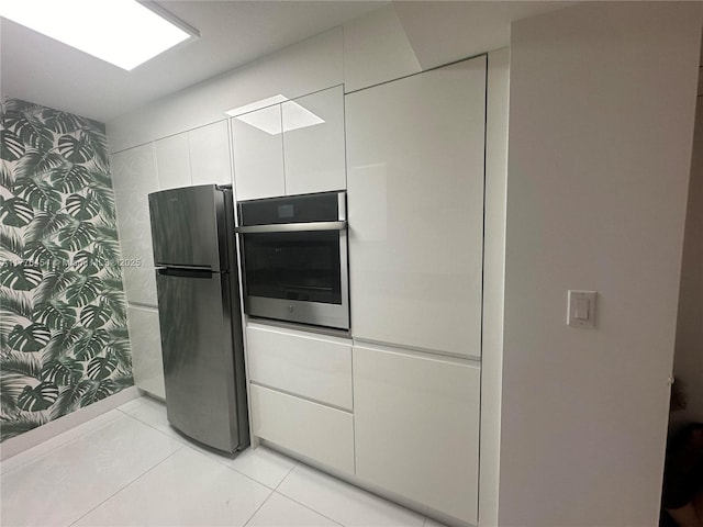 20225 NE 34th St Unit 1022, Aventura, FL 33180 - kitchen with light tile patterned flooring, freestanding refrigerator, wallpapered walls, white cabinets, and oven
