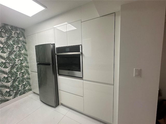 20225 NE 34th St Unit 1022, Aventura, FL 33180 - kitchen featuring oven, wallpapered walls, white cabinetry, light tile patterned floors, and freestanding refrigerator