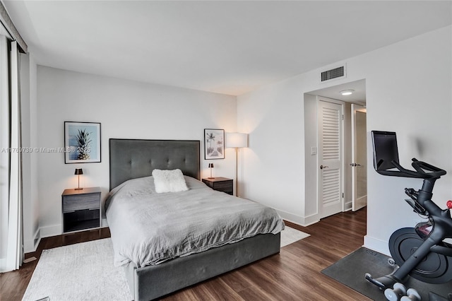 bedroom with baseboards, visible vents, and wood finished floors