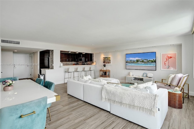 living room featuring baseboards, light wood-style floors, and visible vents