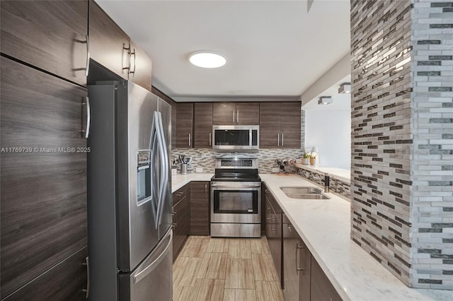 kitchen featuring decorative backsplash, dark brown cabinetry, a sink, and stainless steel appliances
