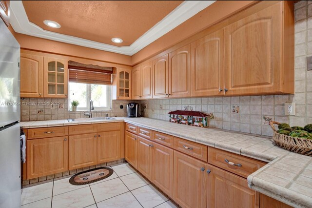 30328 SW 158th Pl, Homestead, FL 33033 - kitchen featuring glass insert cabinets, a sink, freestanding refrigerator, crown molding, and decorative backsplash