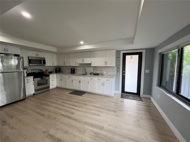 kitchen with baseboards, a sink, stainless steel appliances, and plenty of natural light