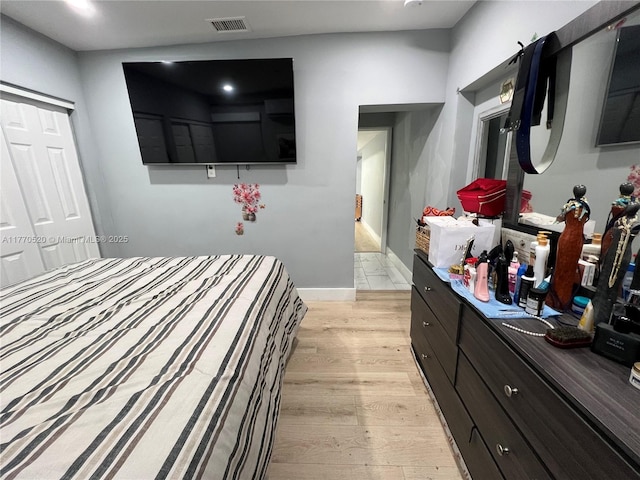 bedroom with baseboards, light wood finished floors, and visible vents