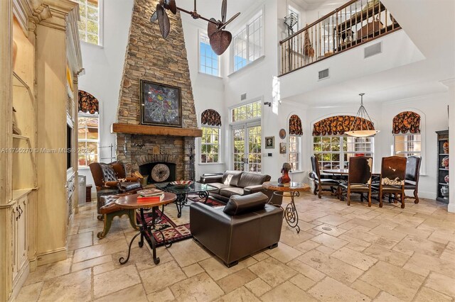 12483 Grand Oaks Dr, Davie, FL 33330 - living area featuring a towering ceiling, stone tile floors, a stone fireplace, ornamental molding, and baseboards