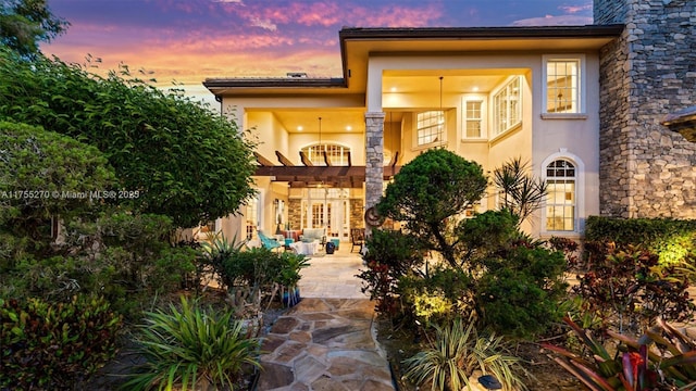 12483 Grand Oaks Dr, Davie, FL 33330 - exterior entry at dusk with stucco siding and a patio