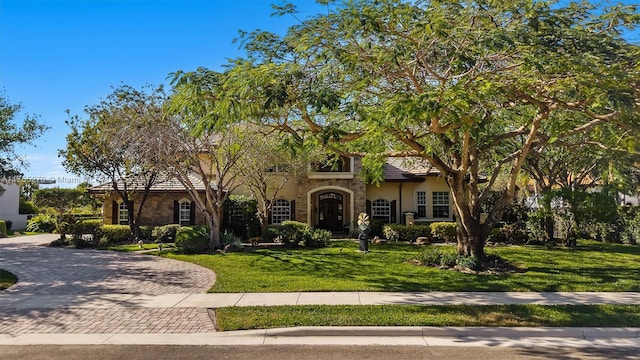 view of front facade featuring a front lawn, decorative driveway, and stucco siding