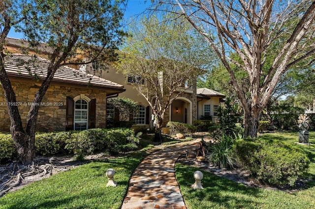 12483 Grand Oaks Dr, Davie, FL 33330 - view of front of home with stone siding, a front yard, and a tile roof