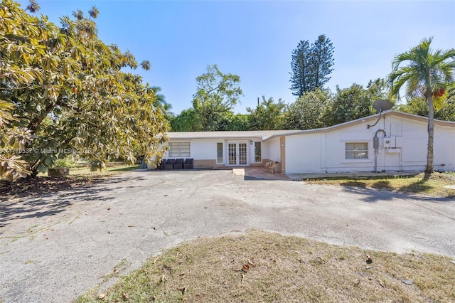ranch-style home with stucco siding, french doors, and aphalt driveway