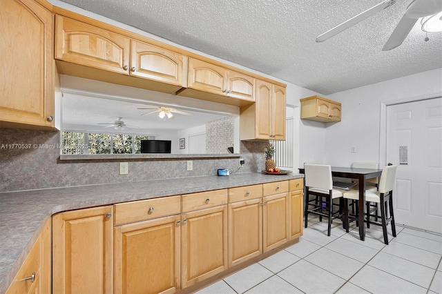 kitchen featuring light tile patterned flooring, light brown cabinets, ceiling fan, and tasteful backsplash