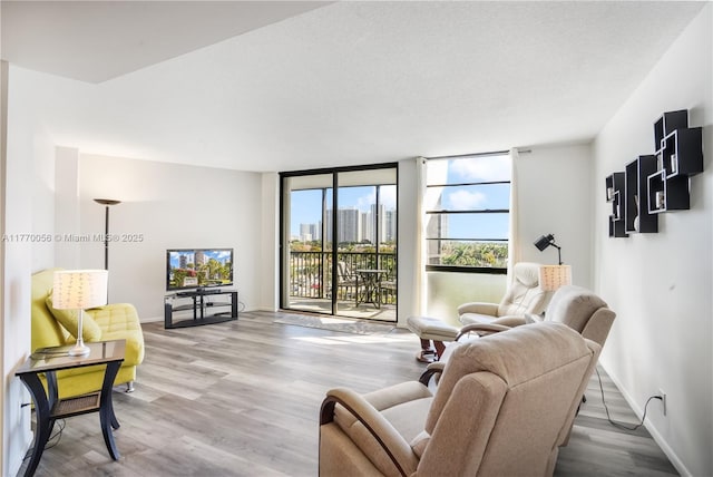 living room featuring baseboards, wood finished floors, and a wall of windows