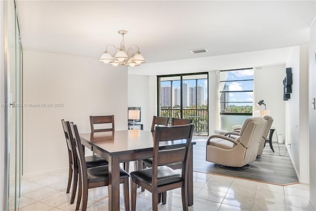 dining area with light tile patterned floors, visible vents, a notable chandelier, and a city view