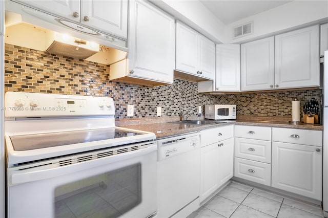 kitchen with tasteful backsplash, under cabinet range hood, white appliances, visible vents, and white cabinets