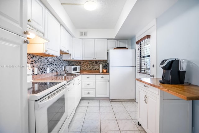 kitchen with white appliances, butcher block countertops, backsplash, visible vents, and white cabinets