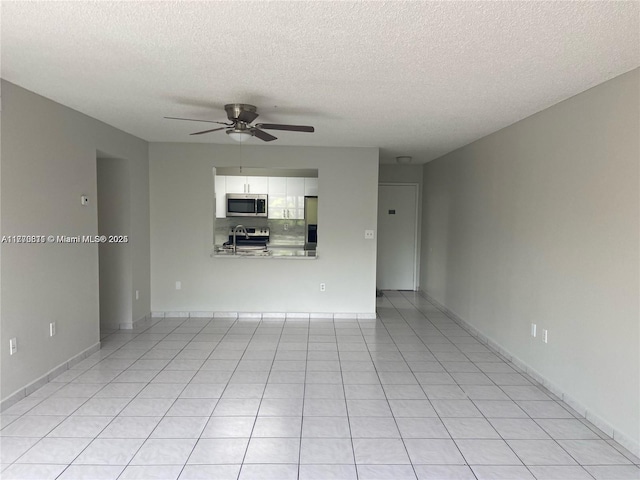unfurnished living room with a textured ceiling, baseboards, light tile patterned floors, and a ceiling fan