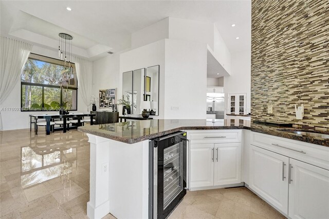 3320 Bridle Path Ln, Weston, FL 33331 - kitchen with wine cooler, dark stone countertops, backsplash, white cabinets, and recessed lighting