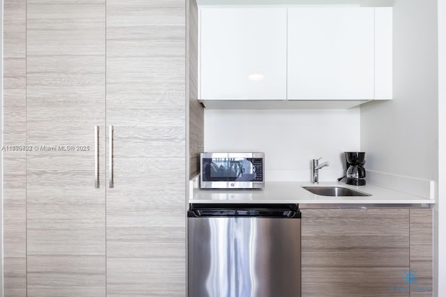 kitchen with white cabinets, modern cabinets, stainless steel microwave, a sink, and dishwashing machine