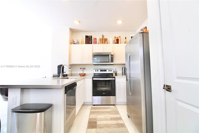 kitchen featuring recessed lighting, stainless steel appliances, a sink, light tile patterned flooring, and a peninsula