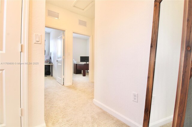 hall with light colored carpet, visible vents, and baseboards