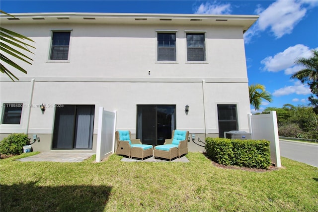 rear view of house with stucco siding and a yard