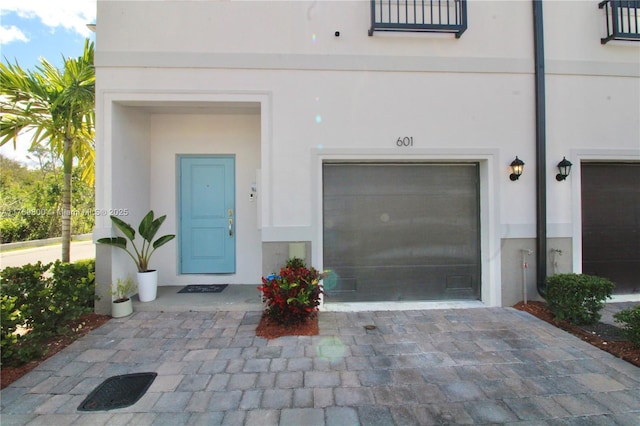 view of exterior entry with decorative driveway and stucco siding