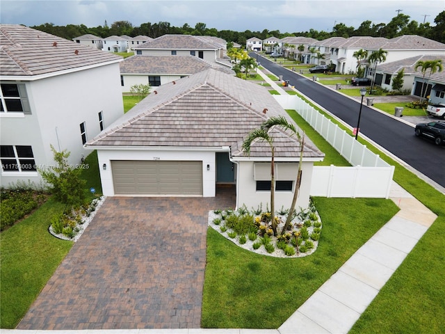 view of front of house with decorative driveway, a garage, a front lawn, a residential view, and stucco siding