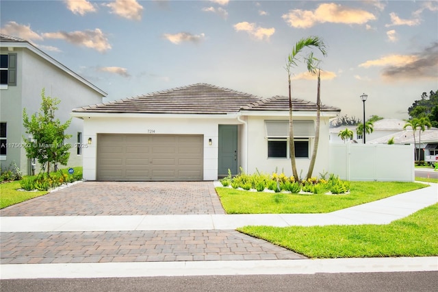 view of front of property with fence, decorative driveway, a garage, a tile roof, and stucco siding