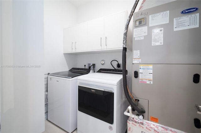 laundry area featuring heating unit, separate washer and dryer, and cabinet space