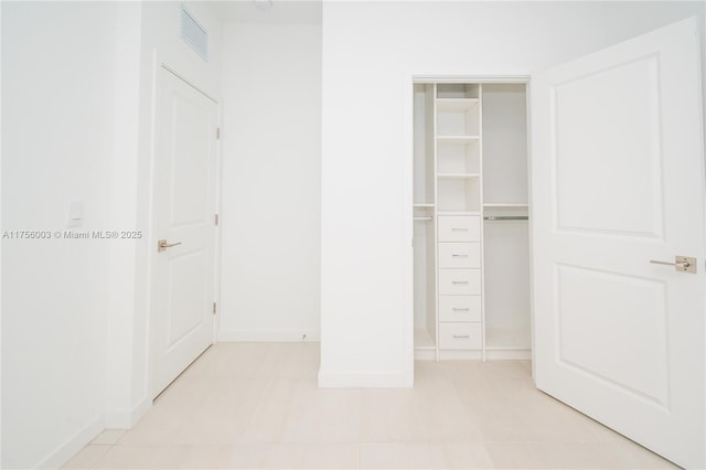 unfurnished bedroom featuring a closet, baseboards, visible vents, and light tile patterned floors