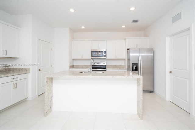 kitchen with a kitchen island with sink, visible vents, stainless steel appliances, and light stone counters
