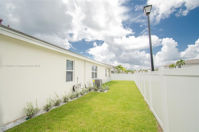 view of yard with central AC unit and a fenced backyard