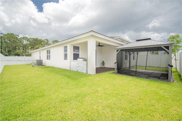 exterior space with a gazebo, cooling unit, a fenced backyard, ceiling fan, and a yard