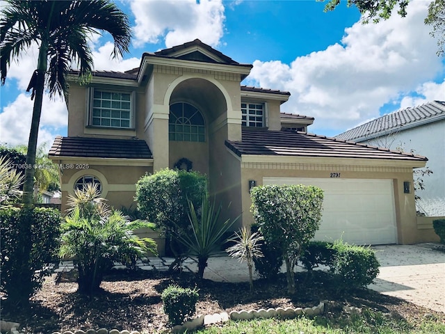 mediterranean / spanish-style home with a tiled roof, stucco siding, and a garage