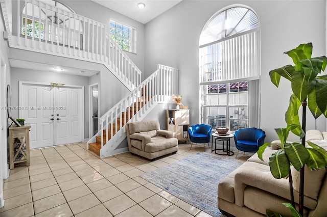 living area with stairs, a high ceiling, and tile patterned floors