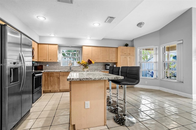 kitchen with appliances with stainless steel finishes, tasteful backsplash, visible vents, and a kitchen bar