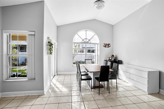 dining room with a healthy amount of sunlight, light tile patterned floors, baseboards, and vaulted ceiling