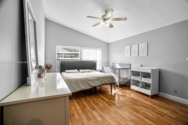 bedroom featuring a textured ceiling, vaulted ceiling, baseboards, and light wood finished floors