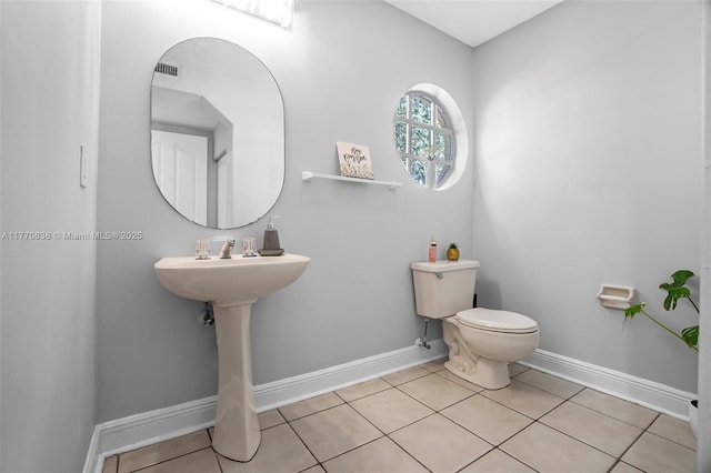 bathroom with baseboards, tile patterned floors, and toilet