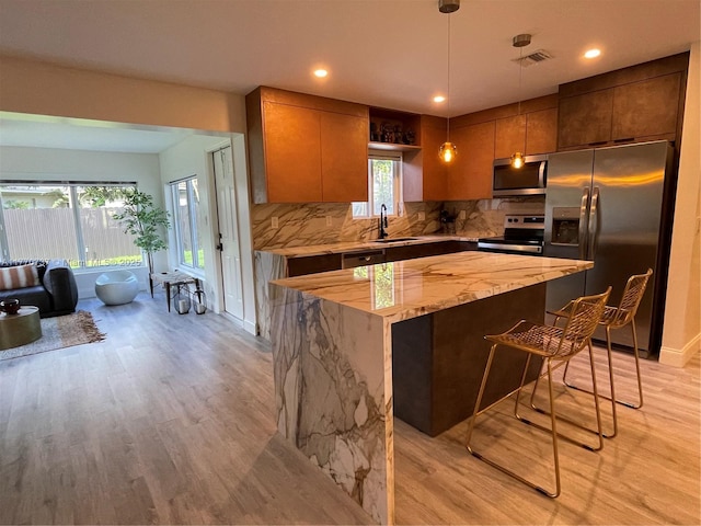 kitchen featuring a sink, a kitchen island, tasteful backsplash, appliances with stainless steel finishes, and visible vents