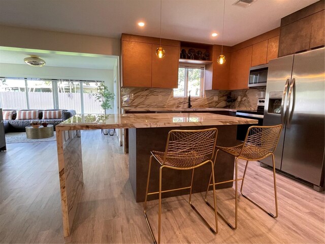 kitchen featuring stainless steel appliances, backsplash, a sink, visible vents, and light wood-style flooring